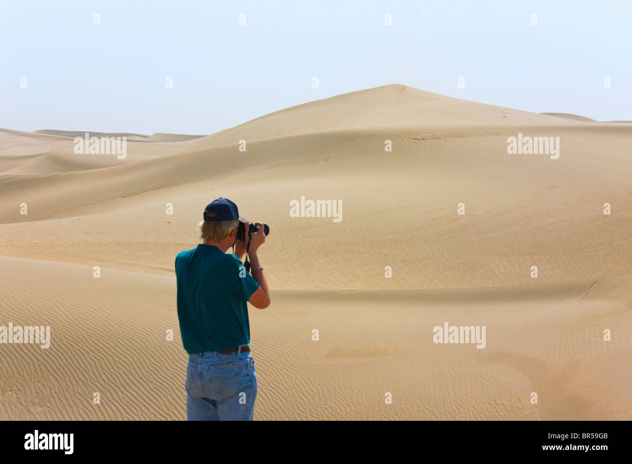 Western tourist photpgrahing sand dunes in the desert, Aksu, Xinjiang, China Stock Photo