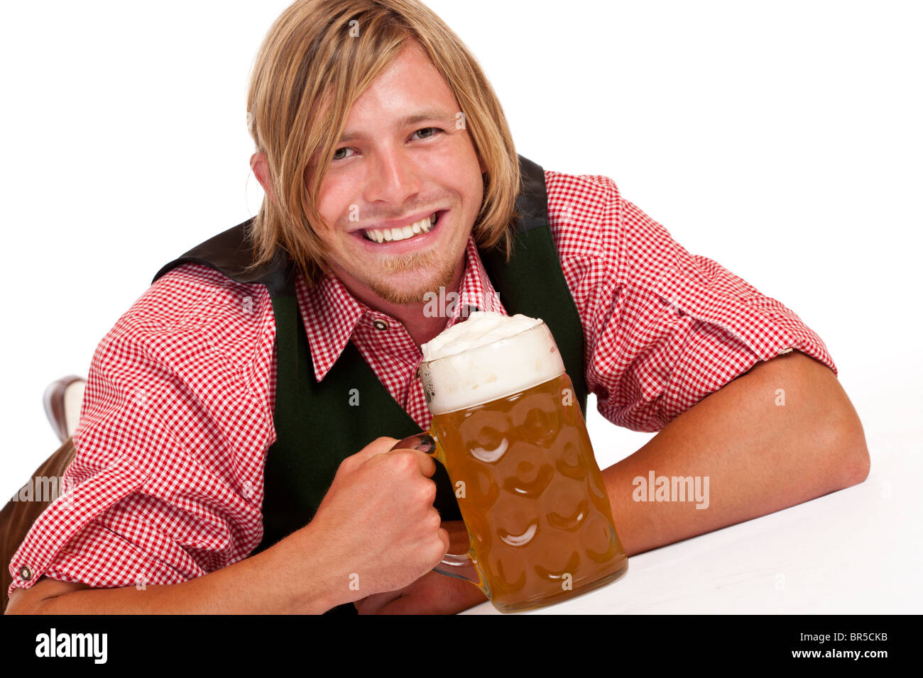 Happy man lying on floor holding Oktoberfest beer stein. Isolated on white background. Stock Photo