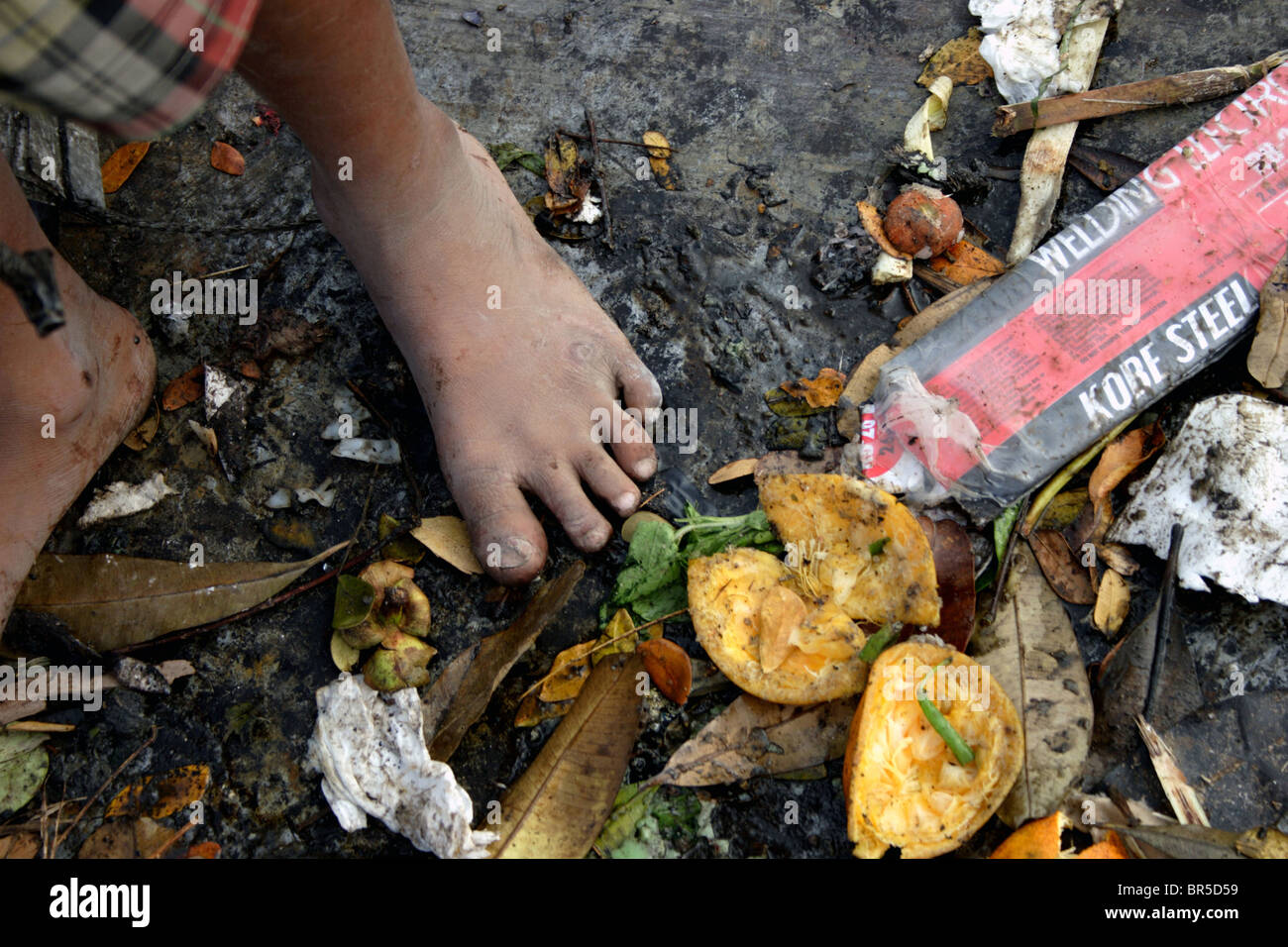 A Young Child Laborer Works Without Shoes While Searching Through Stock Photo Alamy