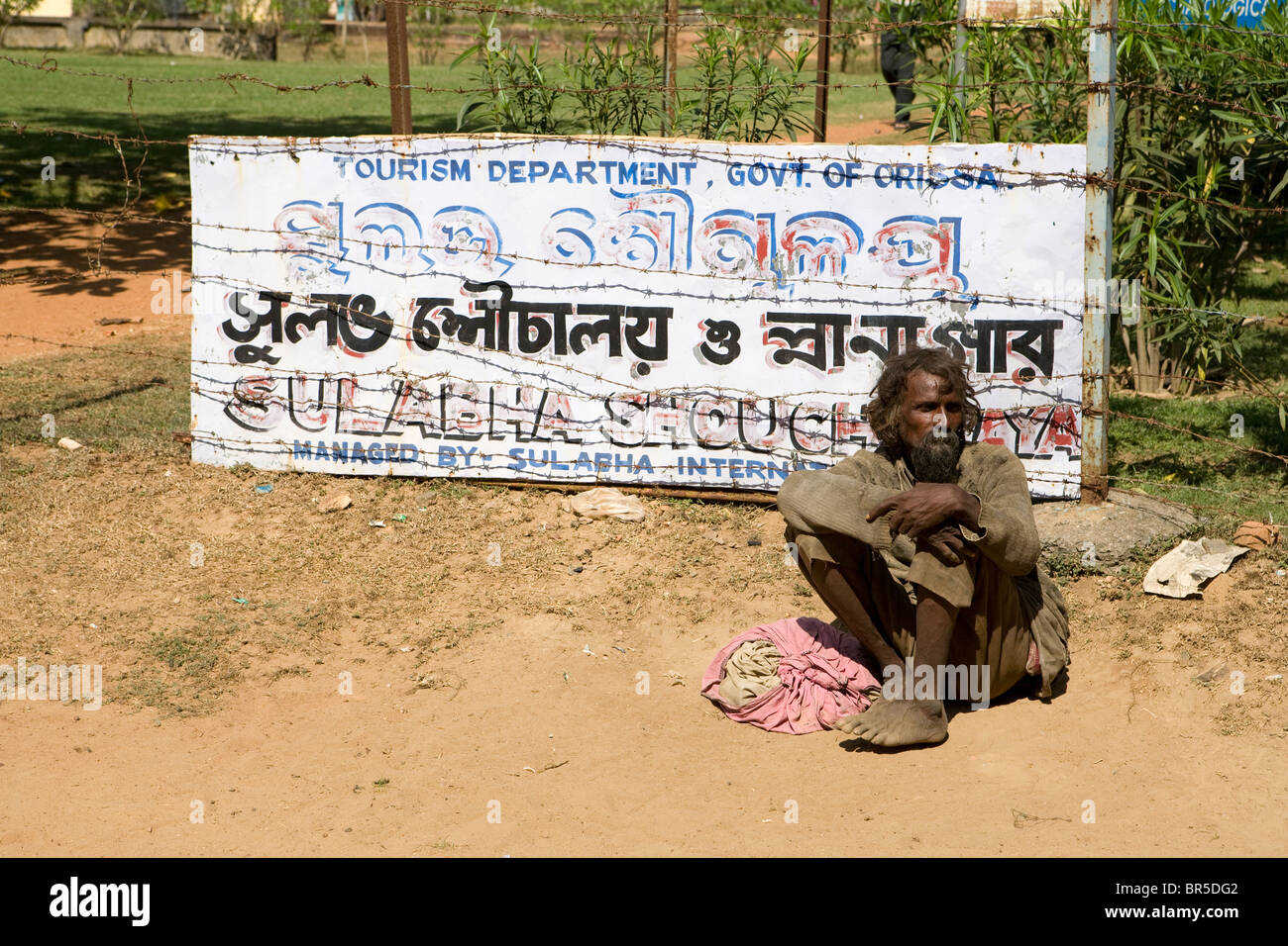Poor Indian man seats on the ground at the entrance of Sun Temple in Orissa. Stock Photo
