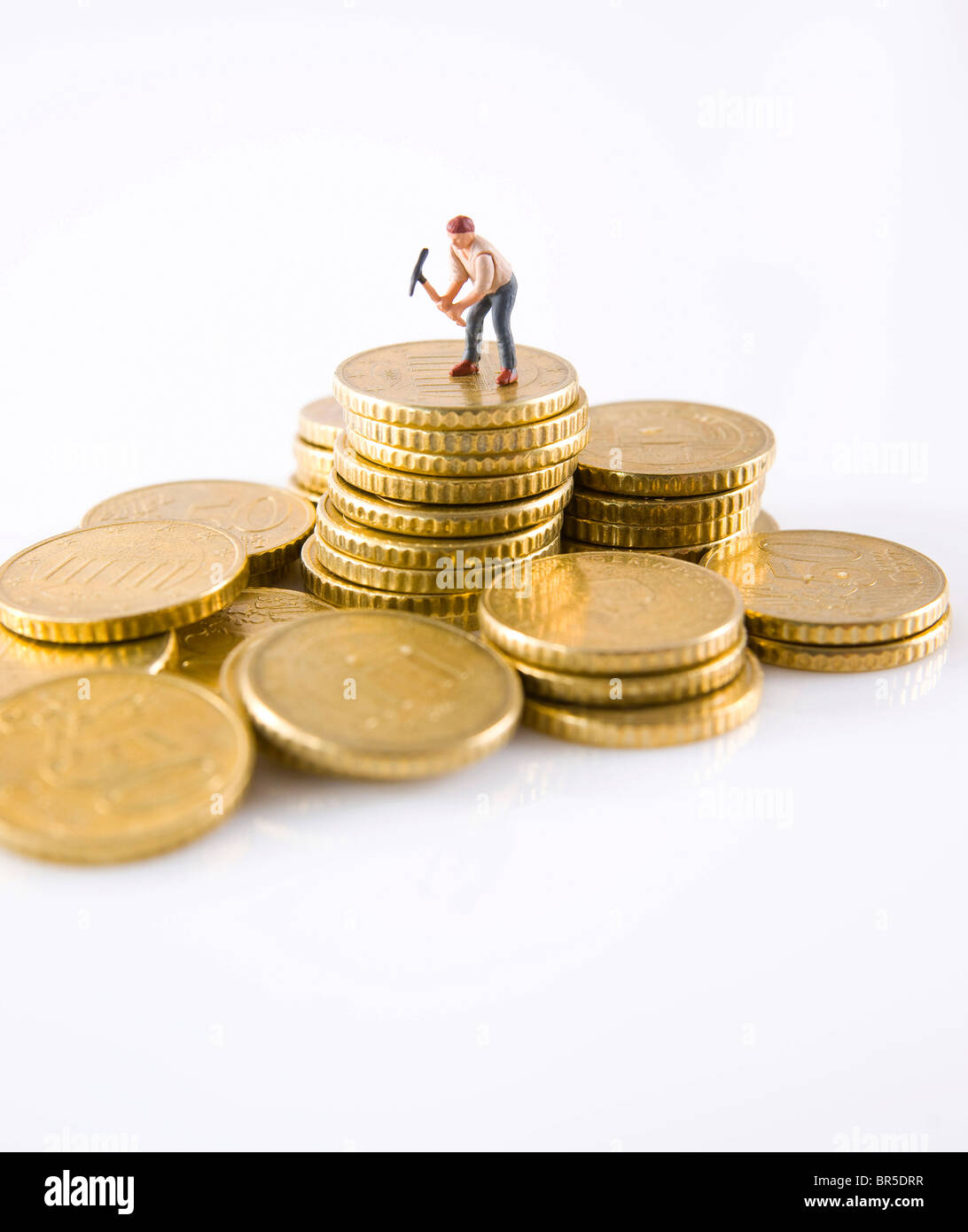 Figur of a man with a pick on a stack of coins Stock Photo