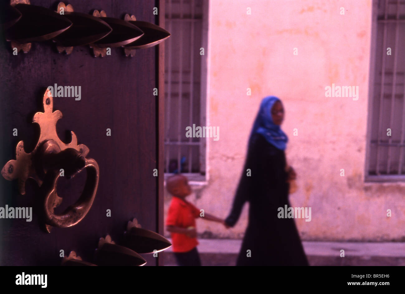 Young Zanzibari woman and child and beautiful wooden door. Stone Town. Zanzibar. Stock Photo