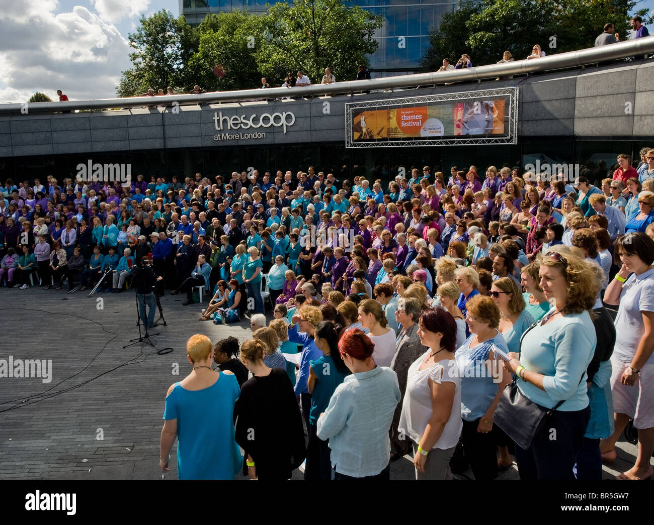 A massed choir singing in the Scoop as part of the Thames Festival in London. Stock Photo
