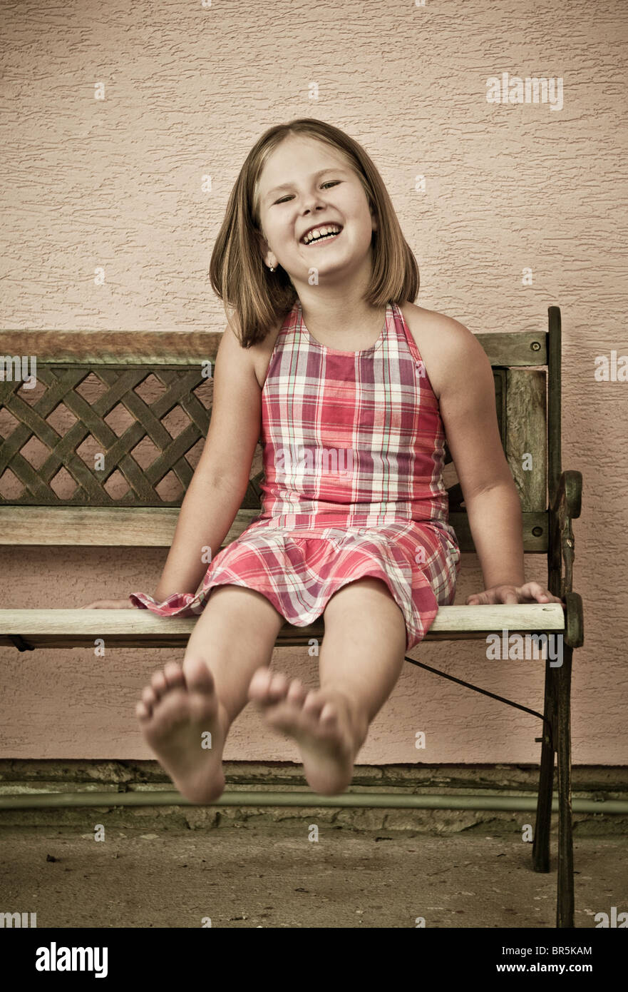 Portrait of cute child sitting on bench and stretching barefoot legs