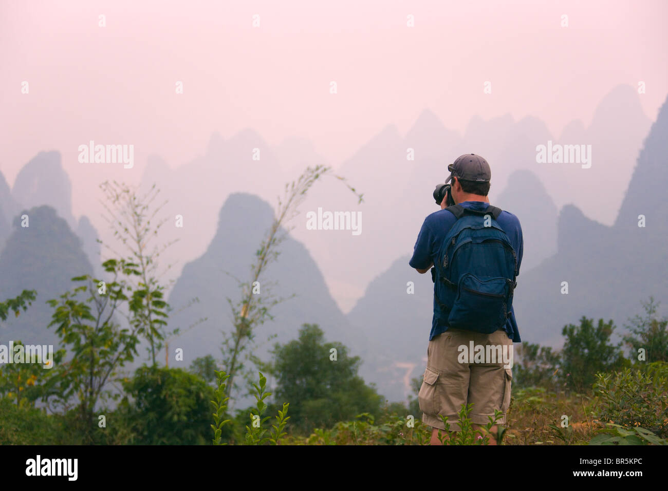 Traveler photographing karst hills along the Li River, Yangshuo, Guangxi, China Stock Photo