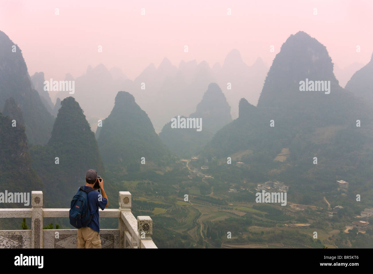 Traveler photographing karst hills and farmland in the Li River area, Yangshuo, Guangxi, China Stock Photo