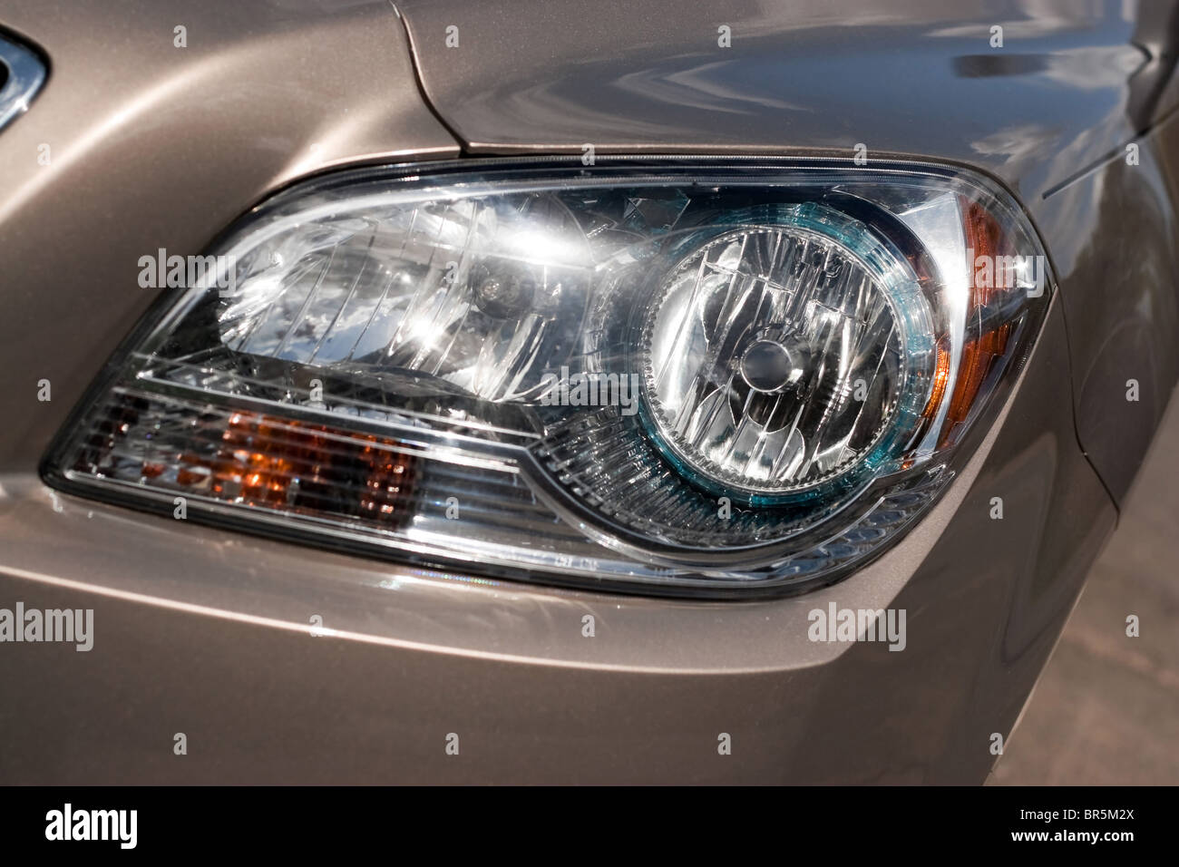 Closeup detail of a car headlight on a modern vehicle with metallic paint. Stock Photo