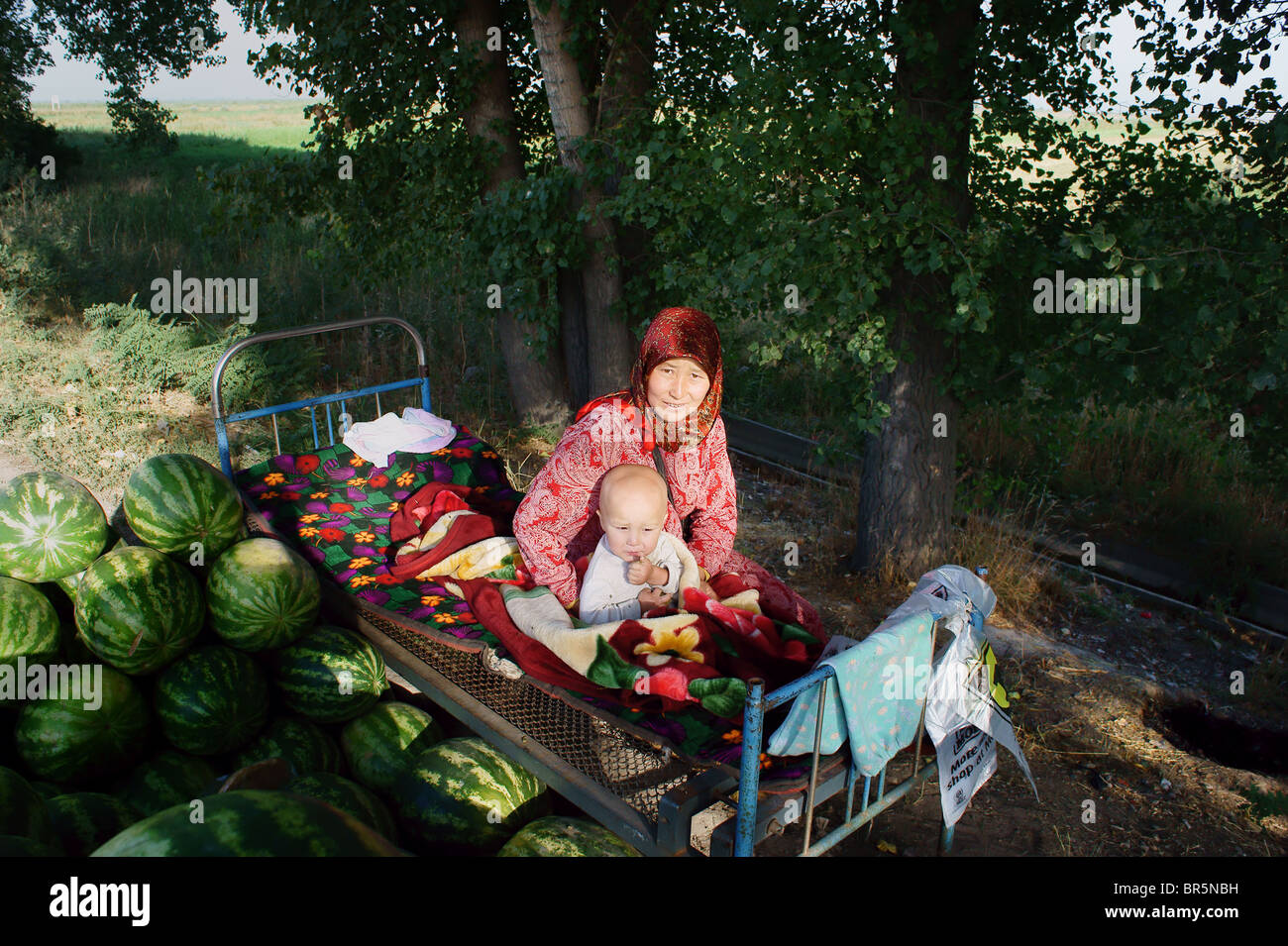 Kyrgyz woman with baby, watermelon seller. Stock Photo