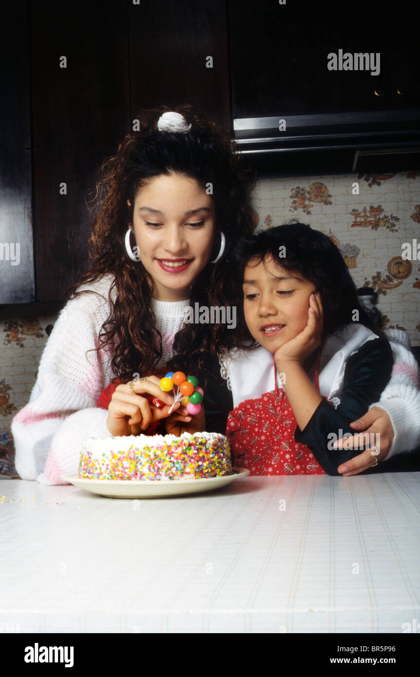 Hispanic Teen Girl Female Big Sister Help Young Decorate Birthday Cake 