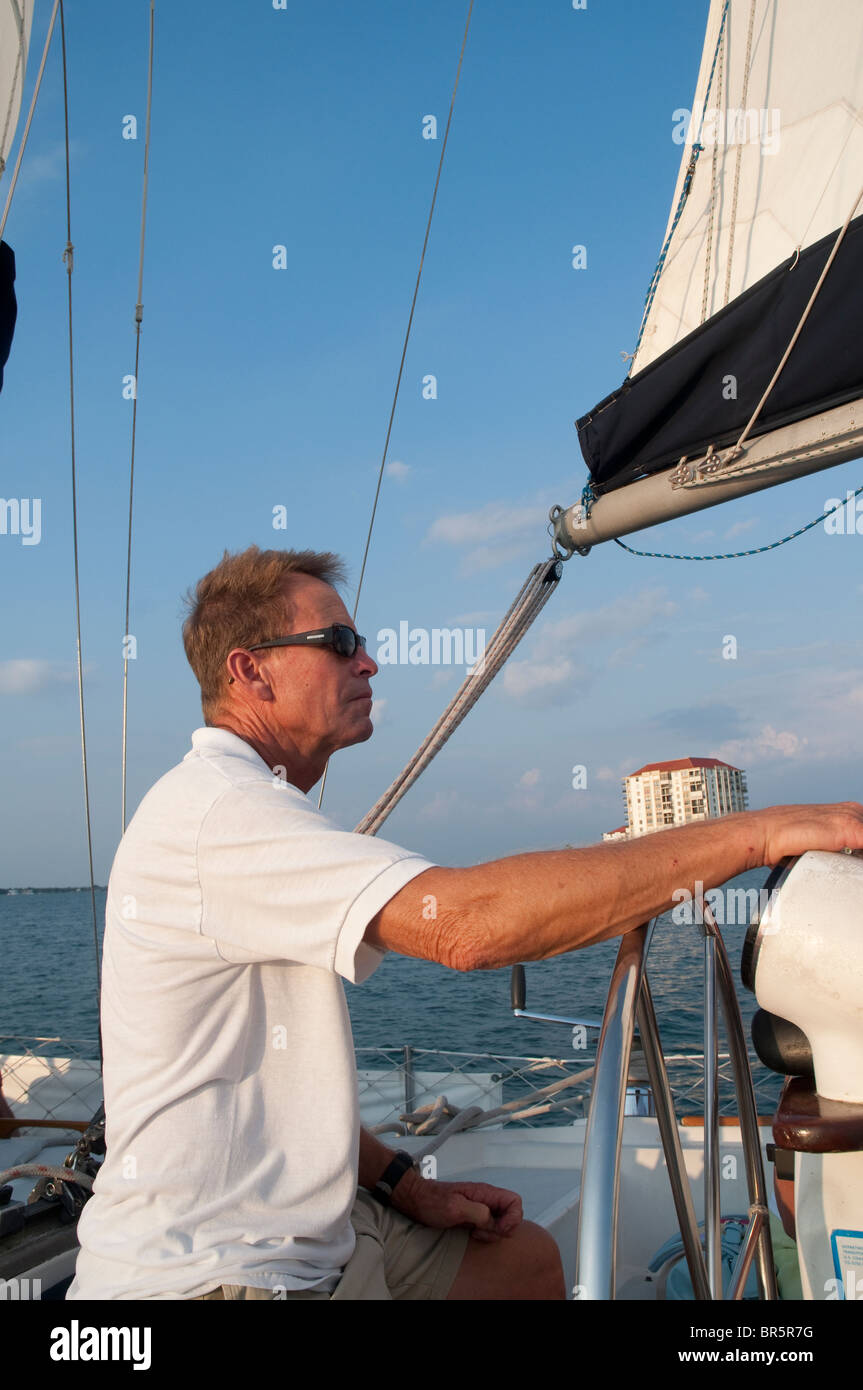 Steering the boat when sunset sailing on yacht from St Pete Beach near St Petersburg Florida USA