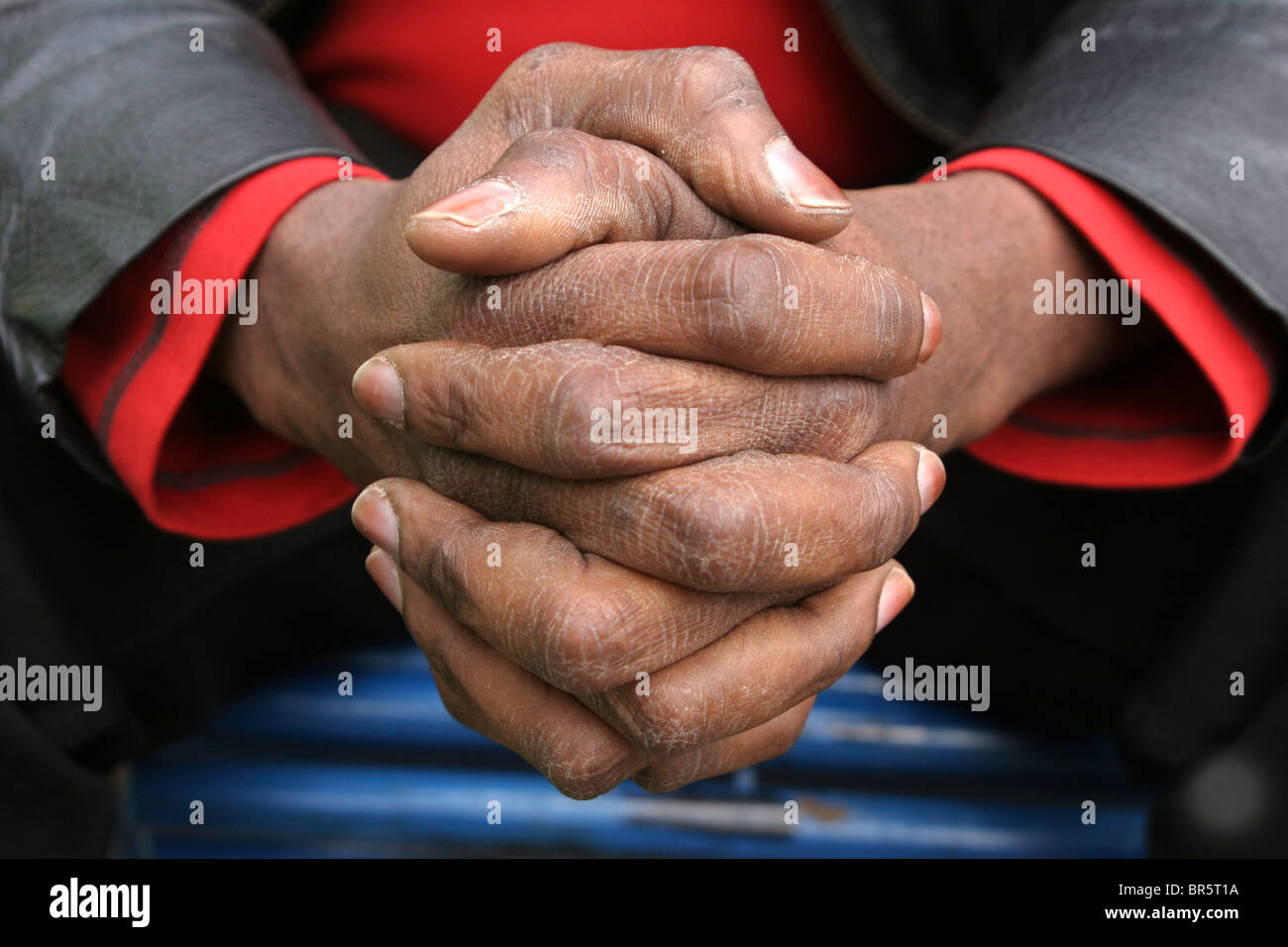 A refugee asylum seeker called Robert who is 42 and from the Democratic Republic of Congo (DRC) clasps his hands. Stock Photo