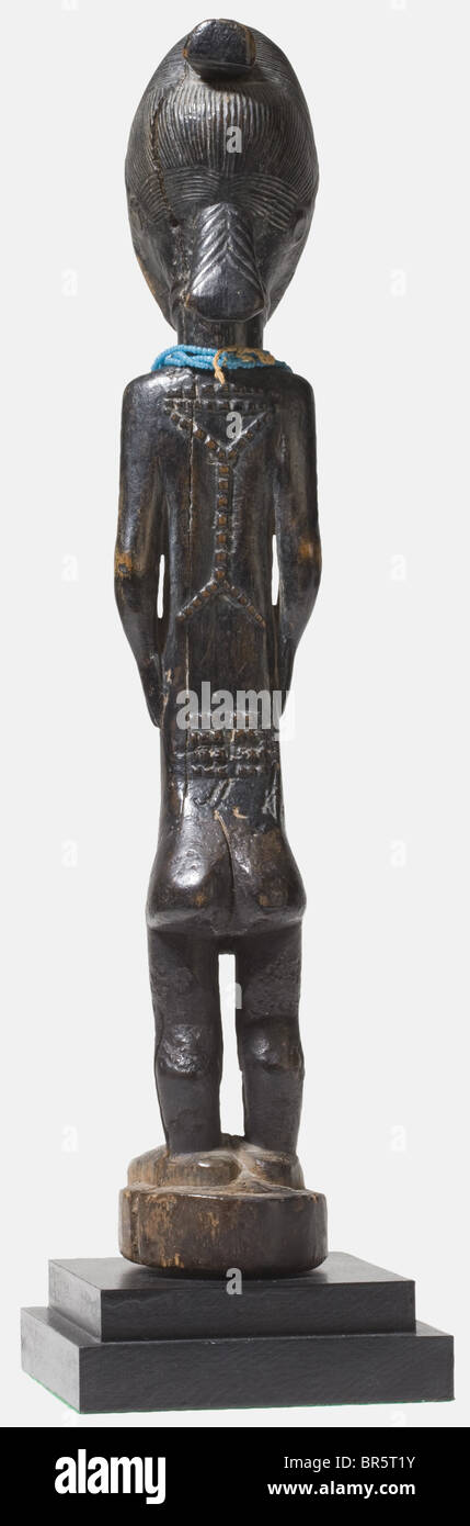A Blolo Bla ancestral figure of the Baule, Ivory Coast Female figure made from blackened wood with a finely carved, elaborate hairstyle, short arms held close to the body as well as short, sturdy legs. Face, belly and back decorated with tribal scars, around the neck a threefold necklace made from glass beads. Colouring somewhat rubbed, on the reverse side and on the sides several cracks. Height without base 44 cm. Cf. Guenneguez, Art de la cote d'ivoire et de ses voisins, Art animiste catalogue des objets extraits de la collection Guenneguez, Edition l'Harmatt, Stock Photo
