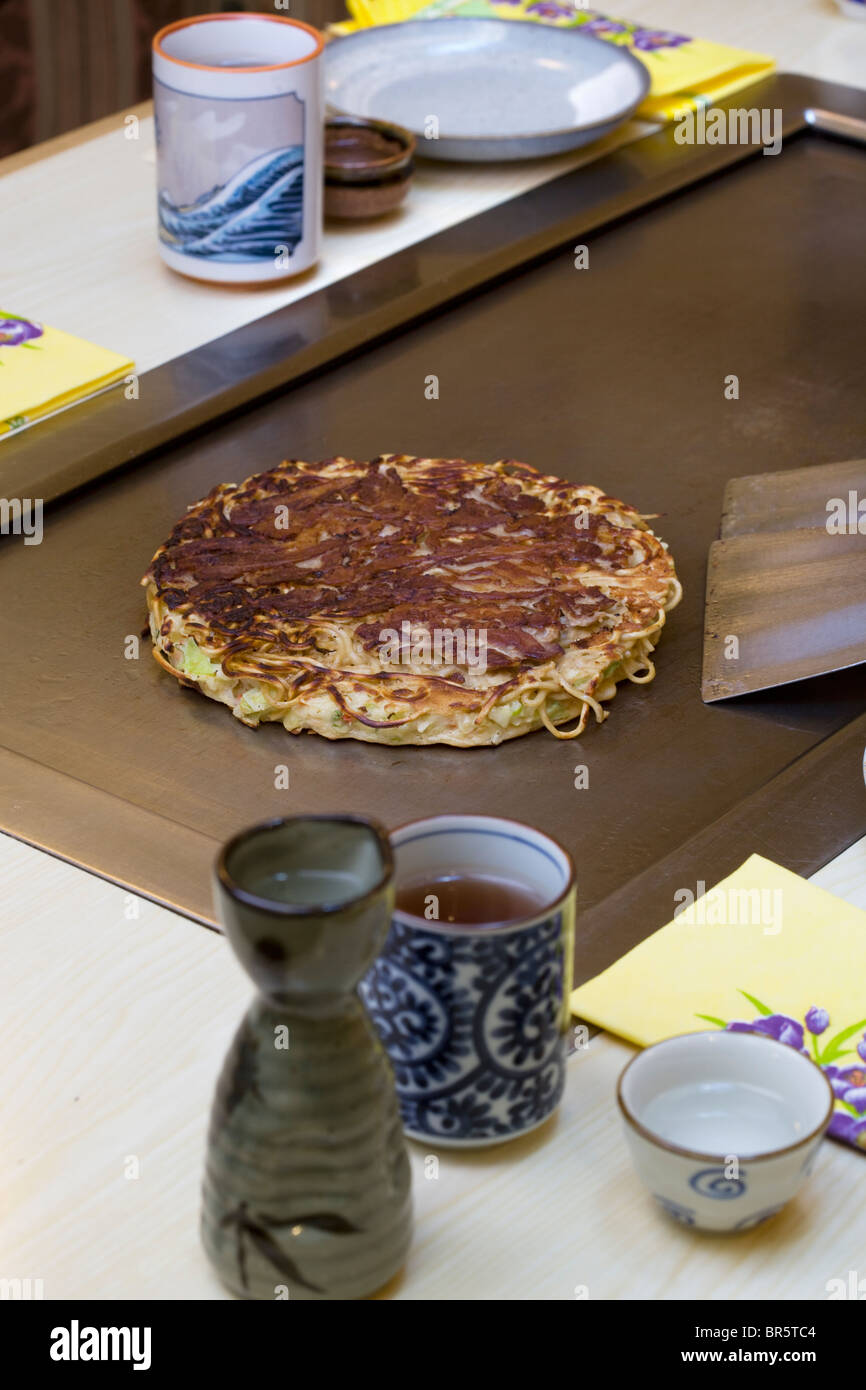 Cooking Pork Okonomiyaki (on the hot-plate) at Abeno Restaurant London England Stock Photo