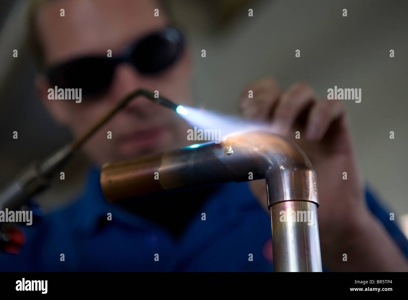 Close up of a heating system engineer, blow torching a copper pipe with