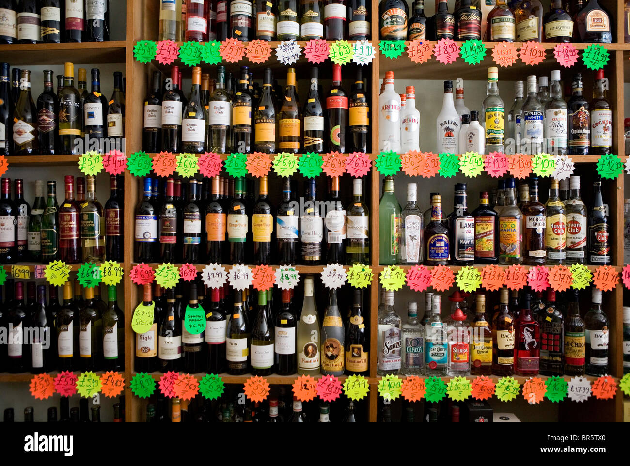 Bottles of wine and spirits stacked on a shelf, awaiting sale in an off-license. Stock Photo