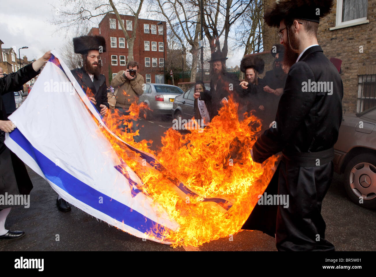 Members of the Ultra Orthodox Jewish anti-Zionist group, the Neturei Karta, burning the Israeli flag. Stamford Hill. Stock Photo