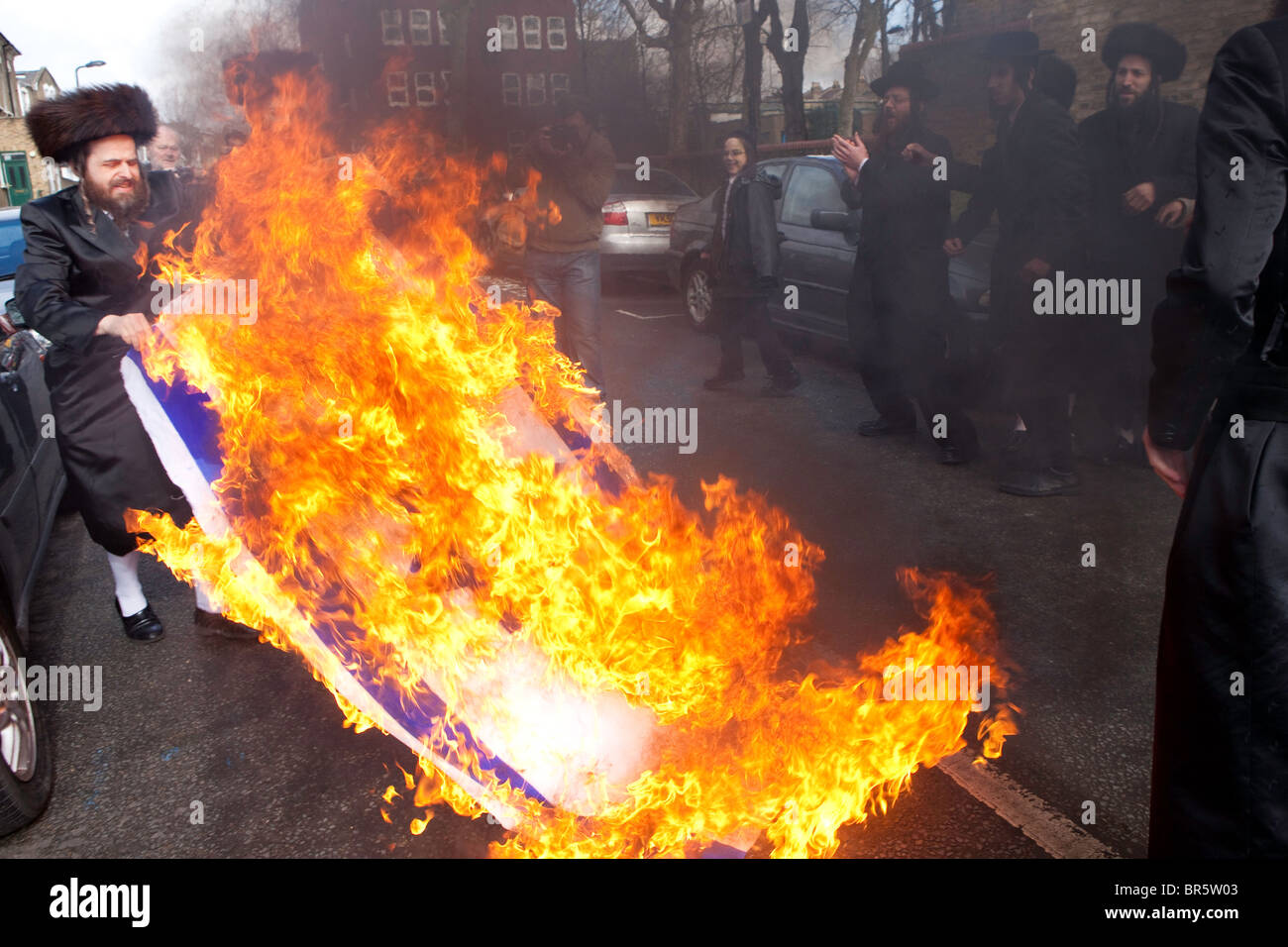 Members of the Ultra Orthodox Jewish anti-Zionist group, the Neturei Karta, burning the Israeli flag. Stamford Hill. Stock Photo