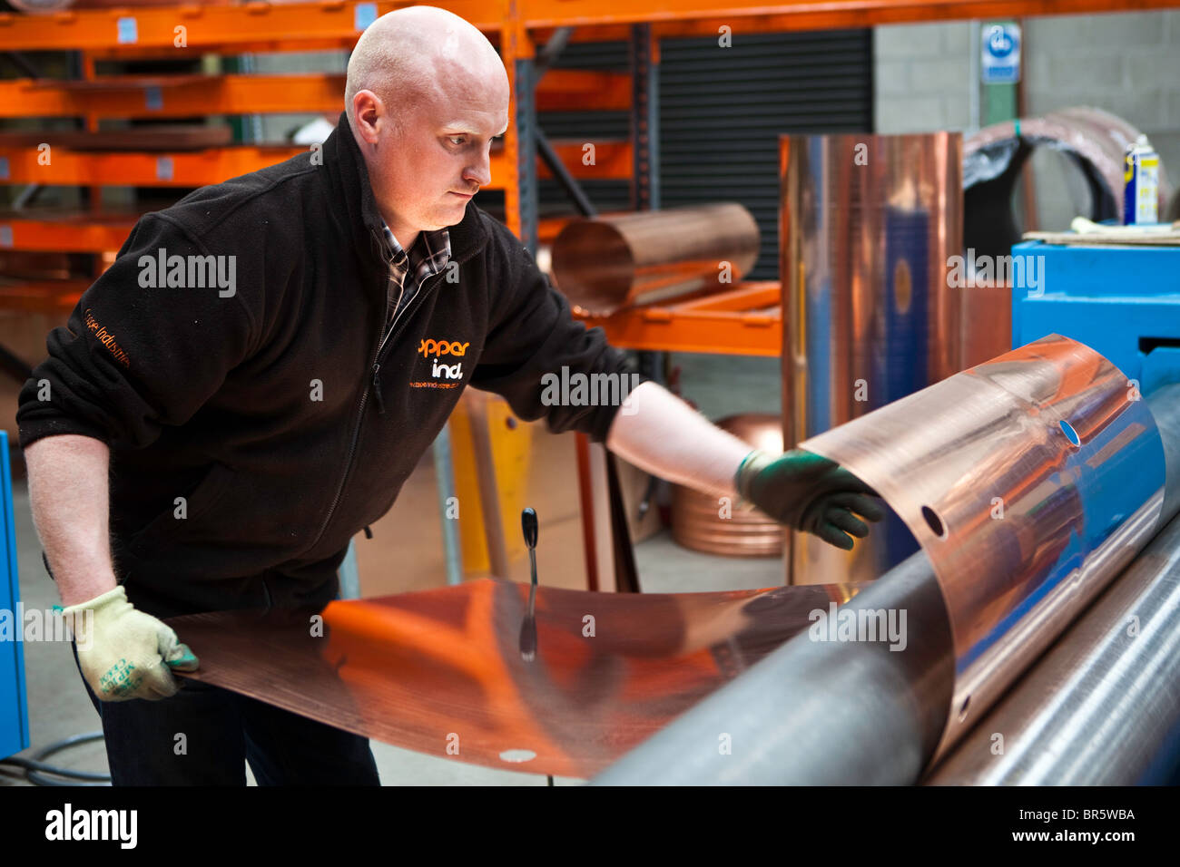 A worker at the Copper Industries factory in Northern Ireland bends copper sheeting for the manufacture of hot water tanks. Stock Photo