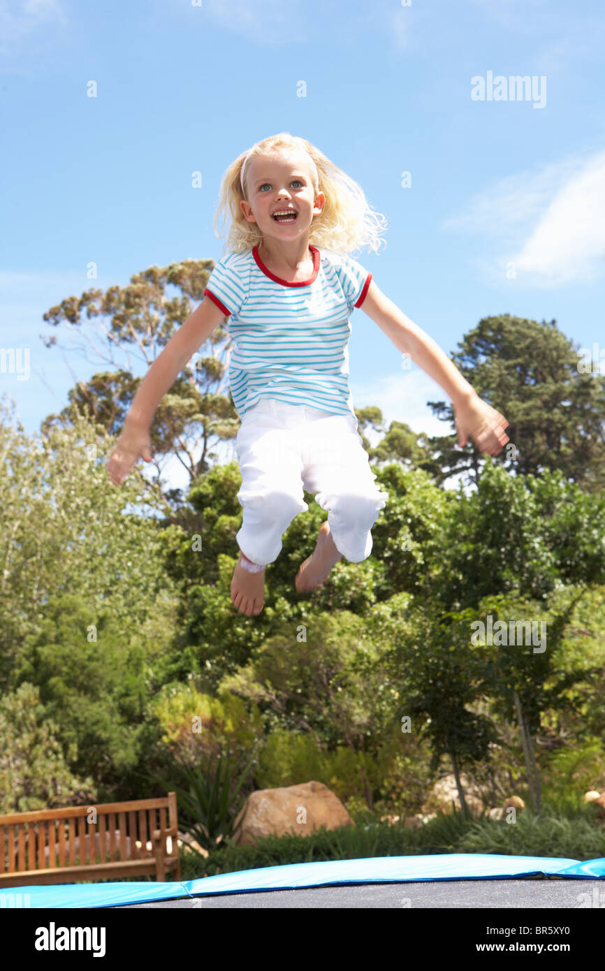 Young Girl Jumping On Trampoline In Garden Stock Photo