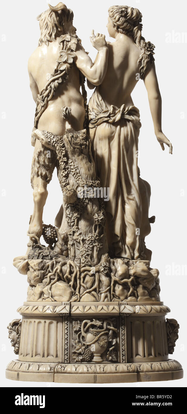 A large German ivory sculpture 'Pan and Nymph', probably Erbach, 2nd half of the 19th century Exceptional carving with depiction of the god of the woods, clad in vine leaves, holding a flute in his left hand, at his side a nymph with thrown-over cloth and flowers, at her feet a young satyr and a childlike nymph. Tiered socket with rich carvings, on the sides satyrs' heads, on the front as well as on the back figurative scenes and floral motifs. Not signed, but with assembling sign 'V' (front) and 'H' (back). Slightly damaged. Height 52.5 cm. CITES cer, Artist's Copyright has not to be cleared Stock Photo
