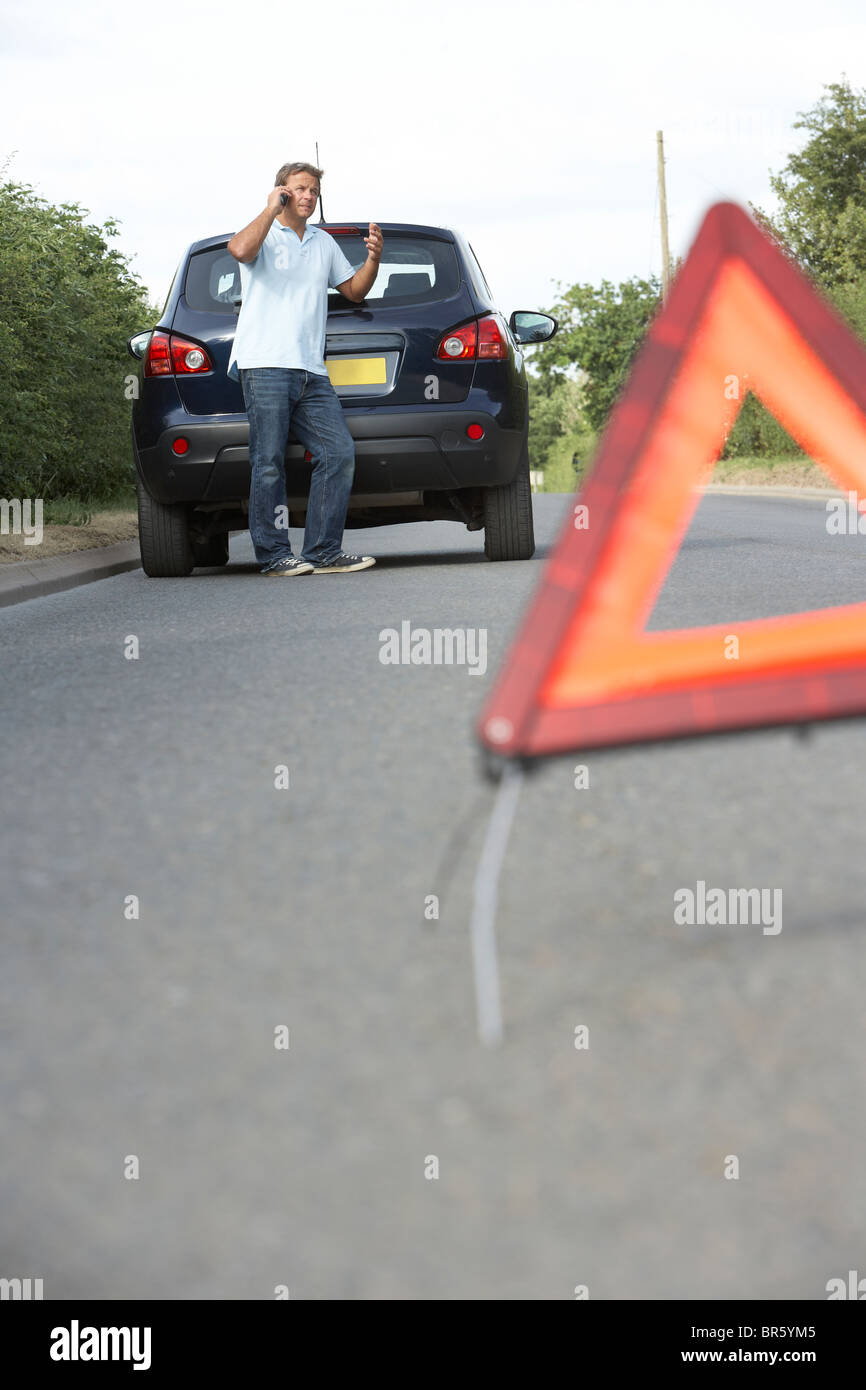 Driver Broken Down On Country Road With Hazard Warning Sign In Foreground Stock Photo