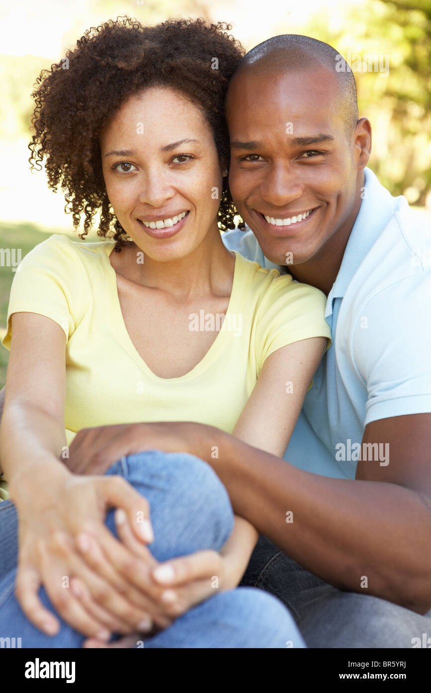 Portrait Of Young Couple Sitting In Park Stock Photo - Alamy