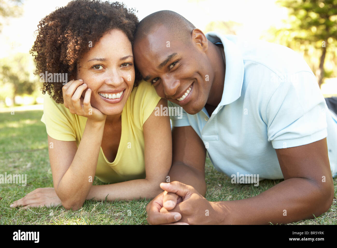 Portrait Of Young Couple Laying On Grass In Park Stock Photo - Alamy
