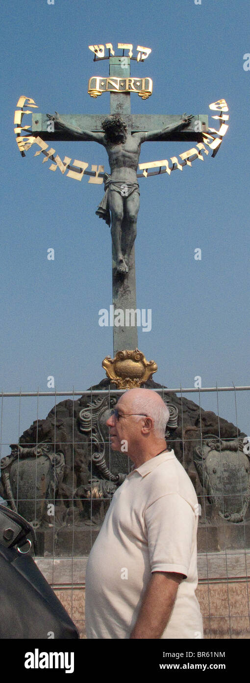Crucifix on Charles Bridge, Prague, fat man passing. Stock Photo