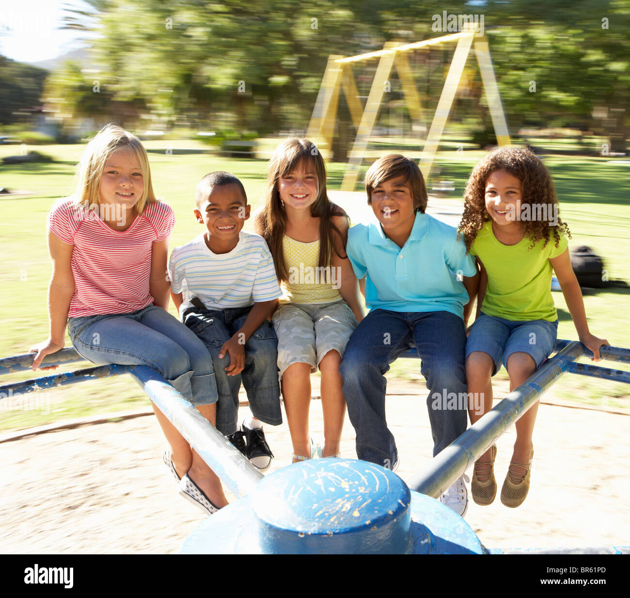 Group Of Children Riding On Roundabout In Playground Stock Photo - Alamy