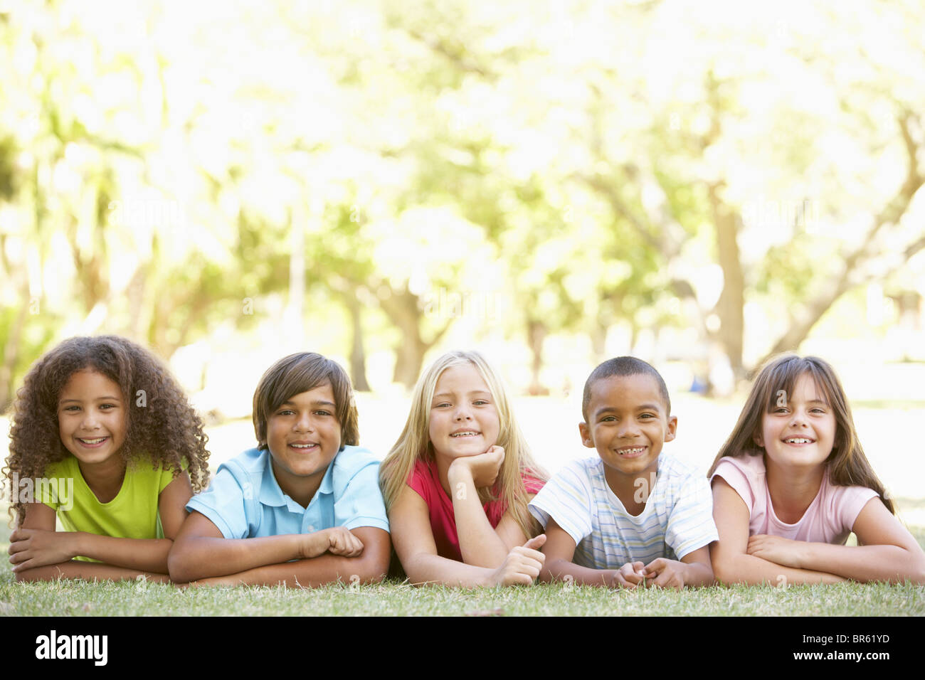 Group Of Children Lying On Stomachs In Park Stock Photo