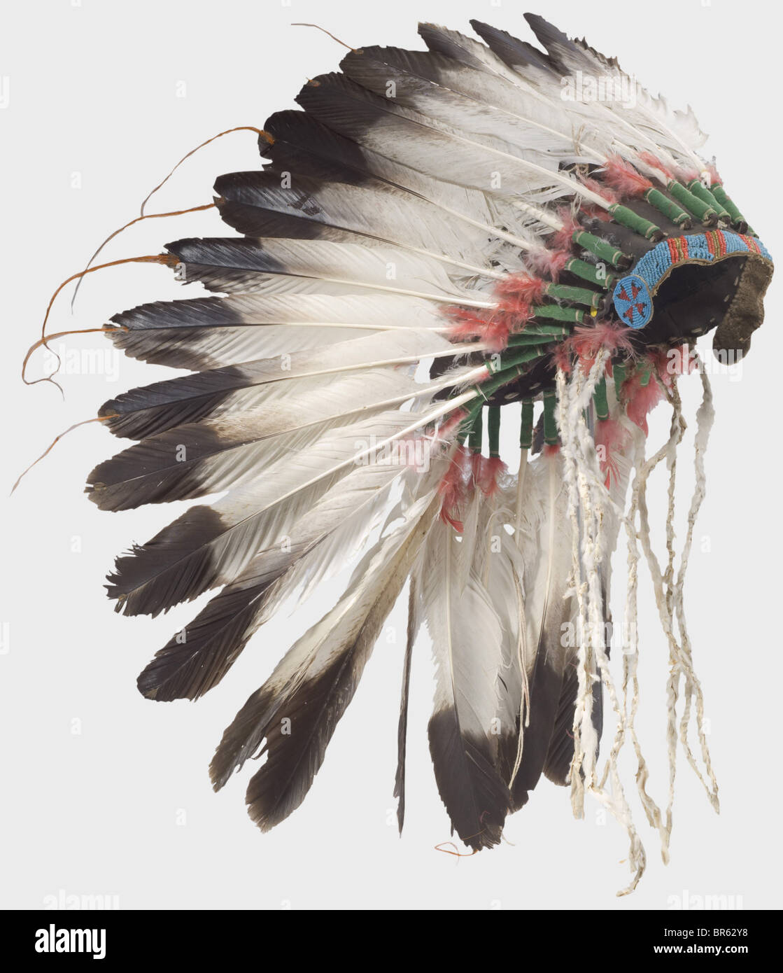 A Plains Indian war bonnet, USA, early 20th century. A crown of large eagle  feathers, the lower section decorated with red dyed down feathers attached  to a felt cap. The forehead section