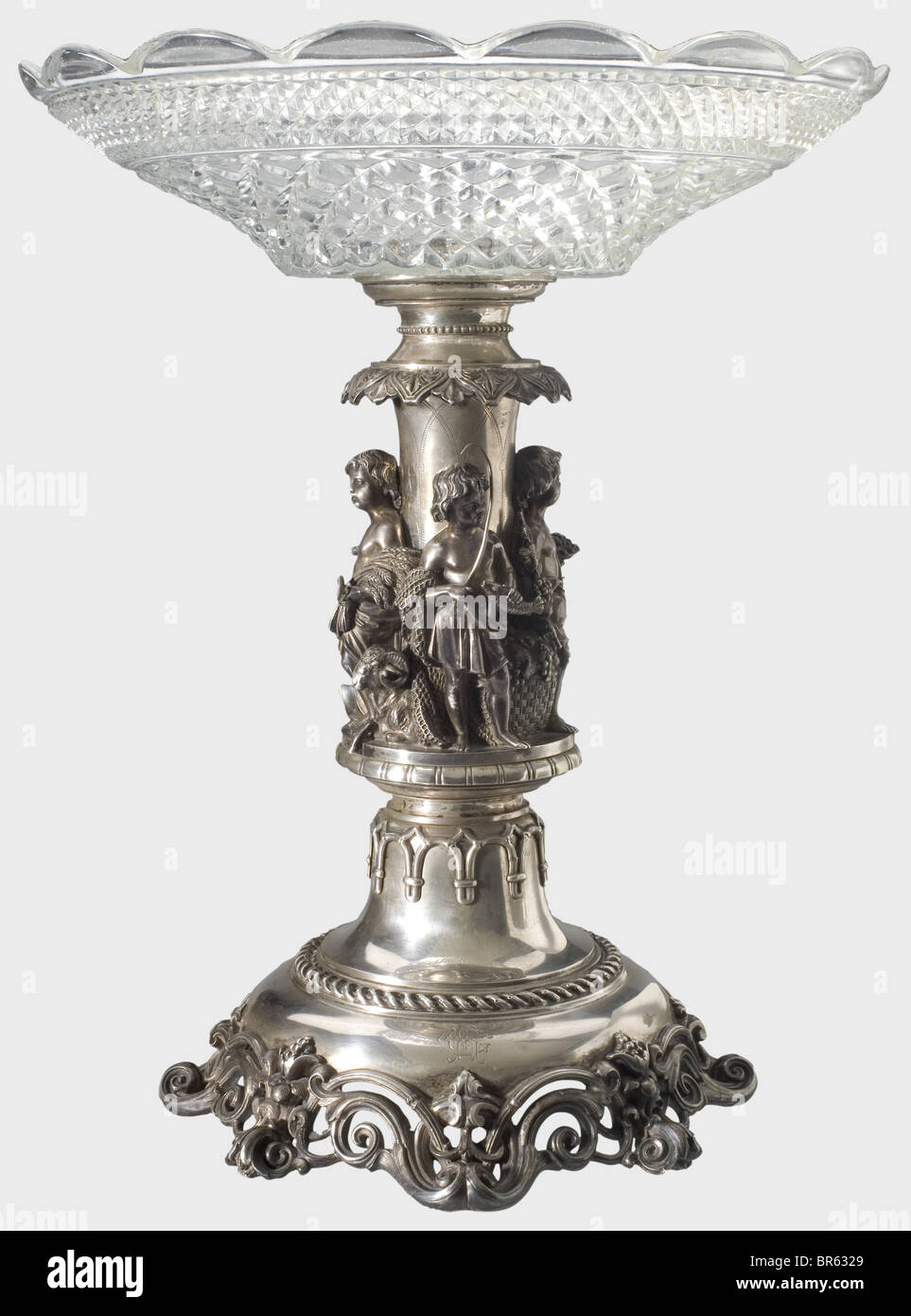 A tazza centrepiece, ca. 1870. Silver foot (no hallmarks). The stem with four three-dimensional genii symbolising fishing, viticulture, hunting and crop/livestock farming. The foot with engraved cipher 'CR'. Height of the stem 36 cm, weight ca. 1750 g. Glass bowl supplemented by moulded glass, diameter 35 cm. fine arts, people, 19th century, handicrafts, handcraft, craft, object, objects, stills, clipping, clippings, cut out, cut-out, cut-outs, vessel, vessels, Artist's Copyright has not to be cleared Stock Photo