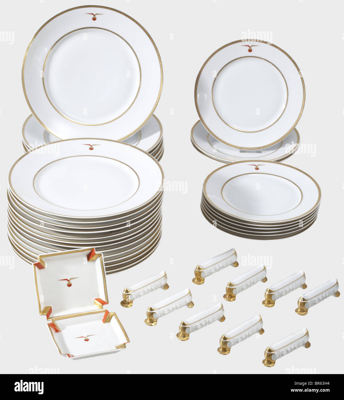 38 porcelain pieces from the service aboard of the Dornier DO X 1929., White, glazed porcelain with decorative lines as well as a stylised, winged globe in gold and red. On the bottom manufacturer's mark in underglaze green 'Gräf & Krippner Selb Bavaria' as well as the golden silhouette of the hydroplane over 'DO X 1929' and most of them inscribed 'Decoration by Marcel Dornier Langenargen'. Consisting of: 19 dining plates, diameter 25.4 cm. Nine dessert plates, diameter 20.3 cm. Two ashtrays, 10.4 x 11.4 cm. Also nine knife rests, with only golden manufactory m, Stock Photo