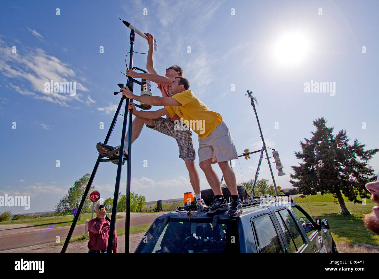 Storm researchers reach to attach the blades of an anemometer atop