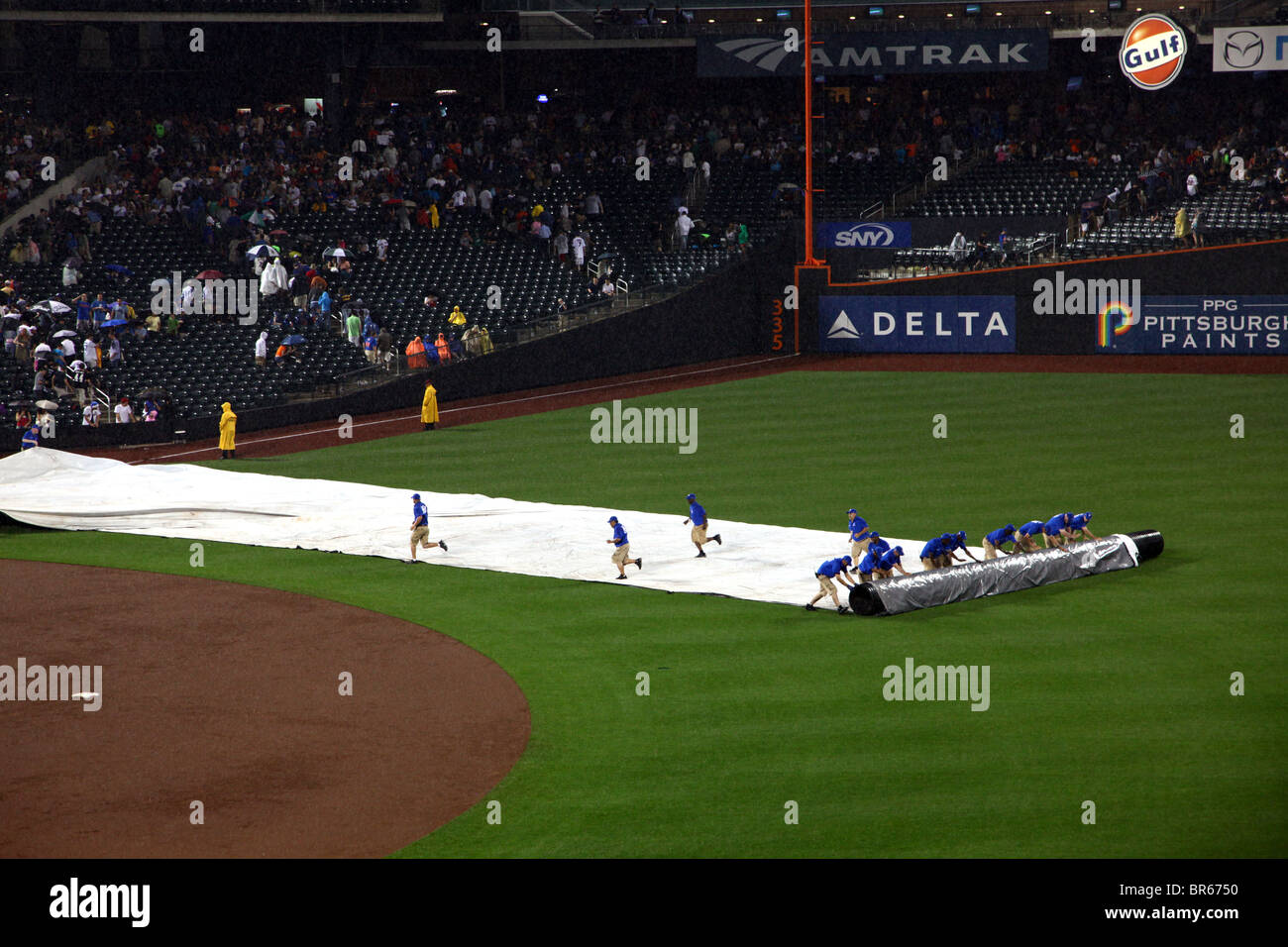 Citi Field grounds crew rolling the tarp on the field after a rain