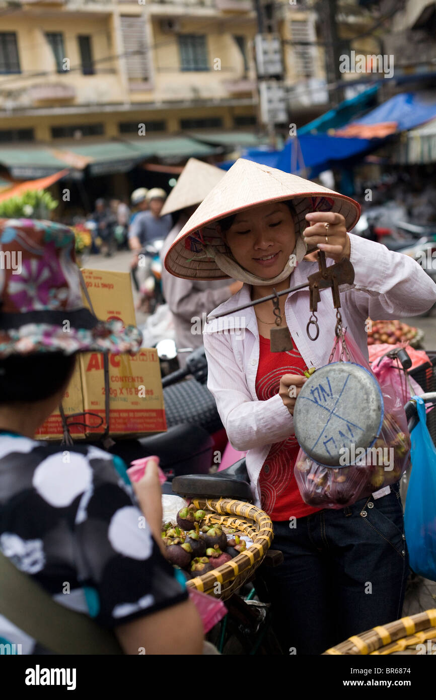Vietnamese fruit vendor weighing bags of fruit for a customer Stock Photo