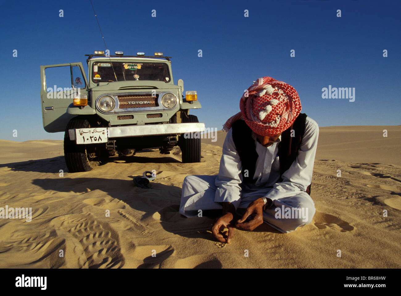 Land cruiser driver plays game in sand on a dune crest near Siwa Oasis Egyptian Western Desert Stock Photo