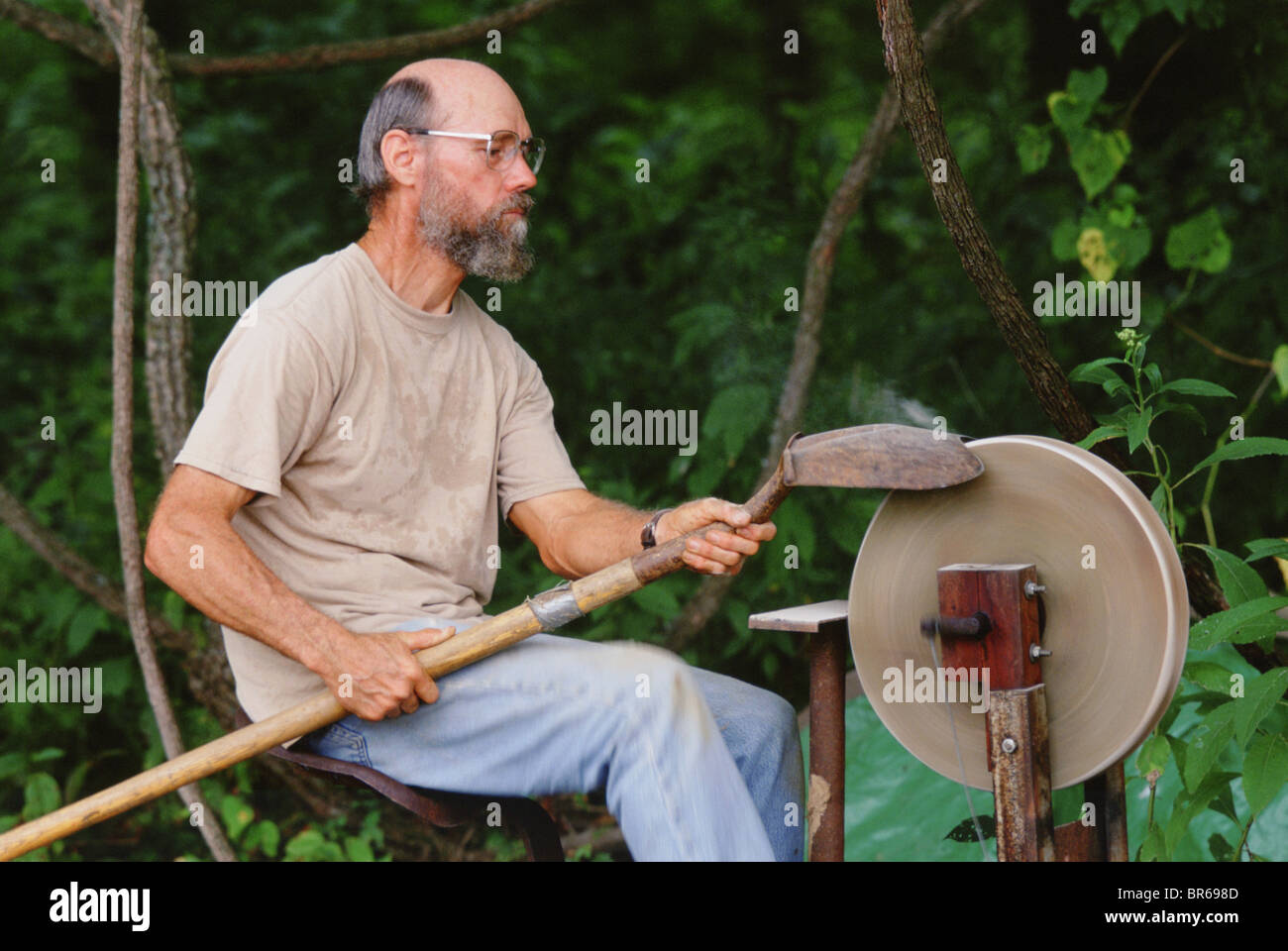 A man sharpening shovels to be used at an archaeological dig at the Big Eddy MO. Stock Photo