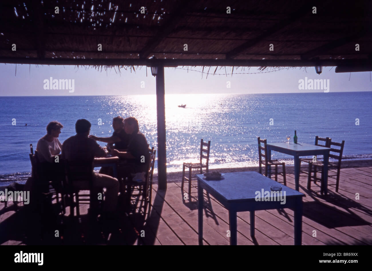 A group of tourists relaxing in a beachfront Taverna at Skala Eressos. Stock Photo