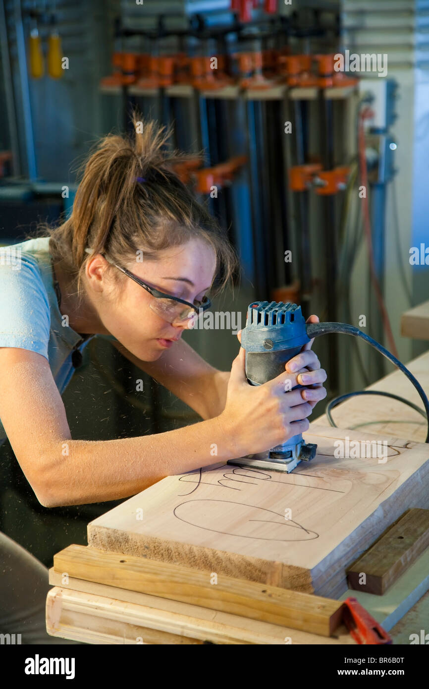 Young female apprentice using a router in a wood-shop. Stock Photo