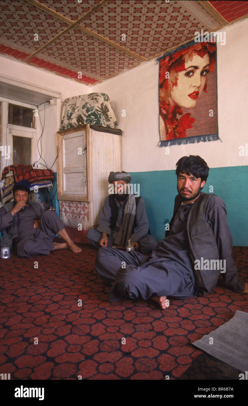Male guests sit below a portrait of a girl at a tea house in Bamiyan Stock Photo