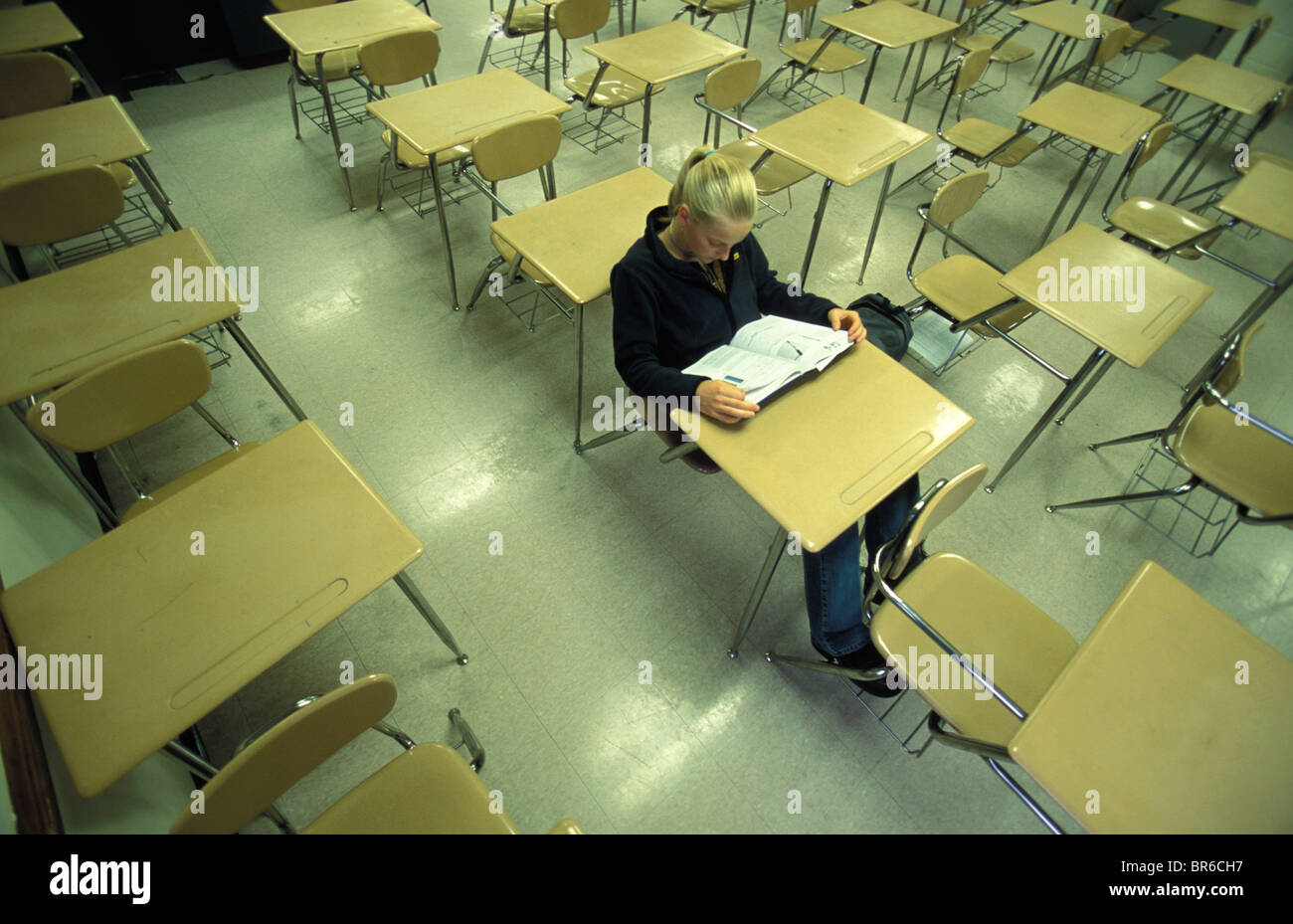 A teenage girl sits at a desk in an empty classroom Stock Photo - Alamy