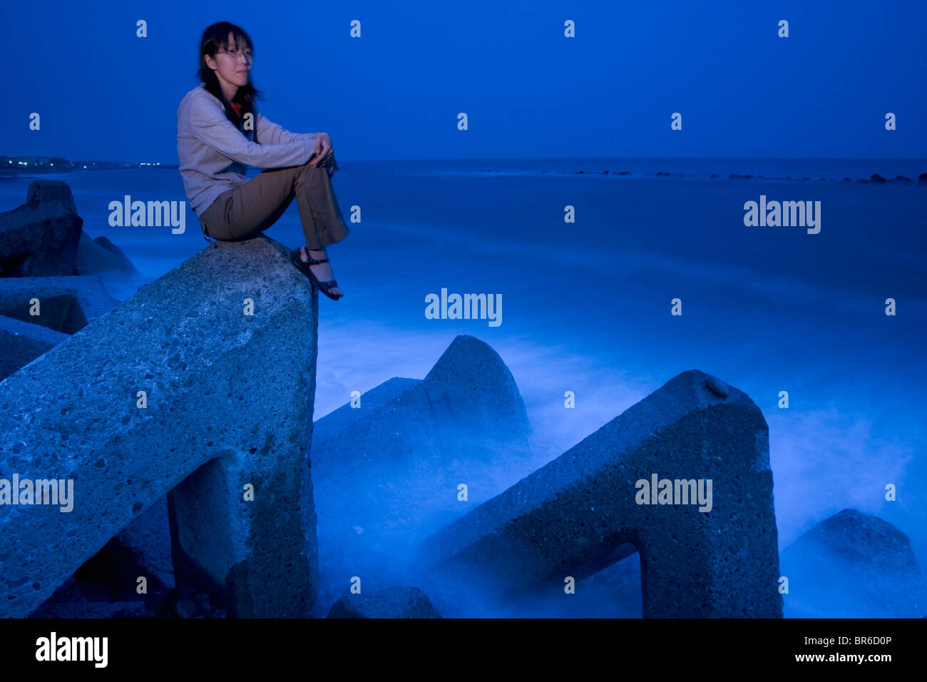 Earthquake scientist sits by the ocean at dusk. Stock Photo