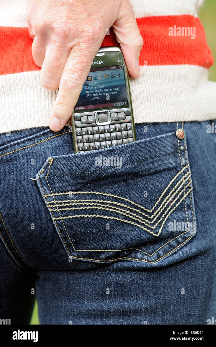 Woman putting a Nokia E71 model mobile phone into her blue jeans pocket Stock Photo