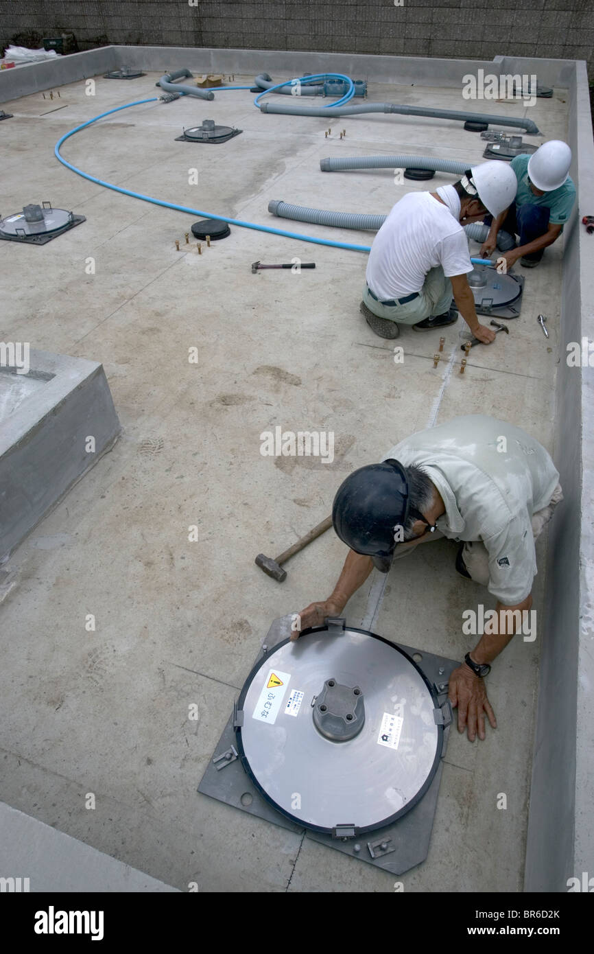 workers install ball bearing sliders to Earthquake-proof a house. Stock Photo