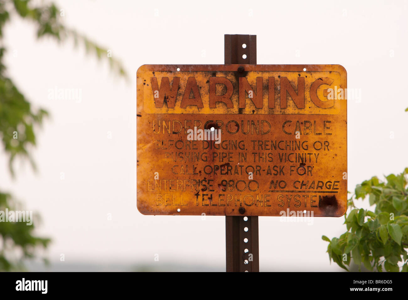 A rusted out sign warning of an underground cable in Oklahoma. RF Stock Photo