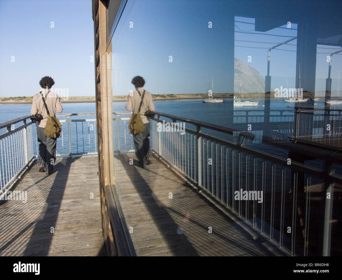 Tourist reflected in a window overlooking Morro Bay harbor California