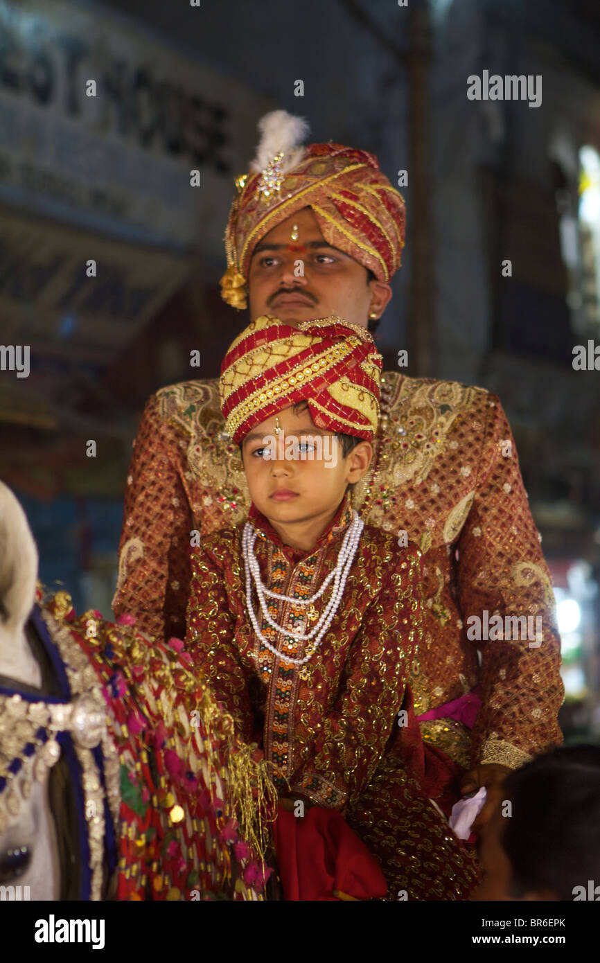 boy and man in traditional indian costumes on a horse for a wedding