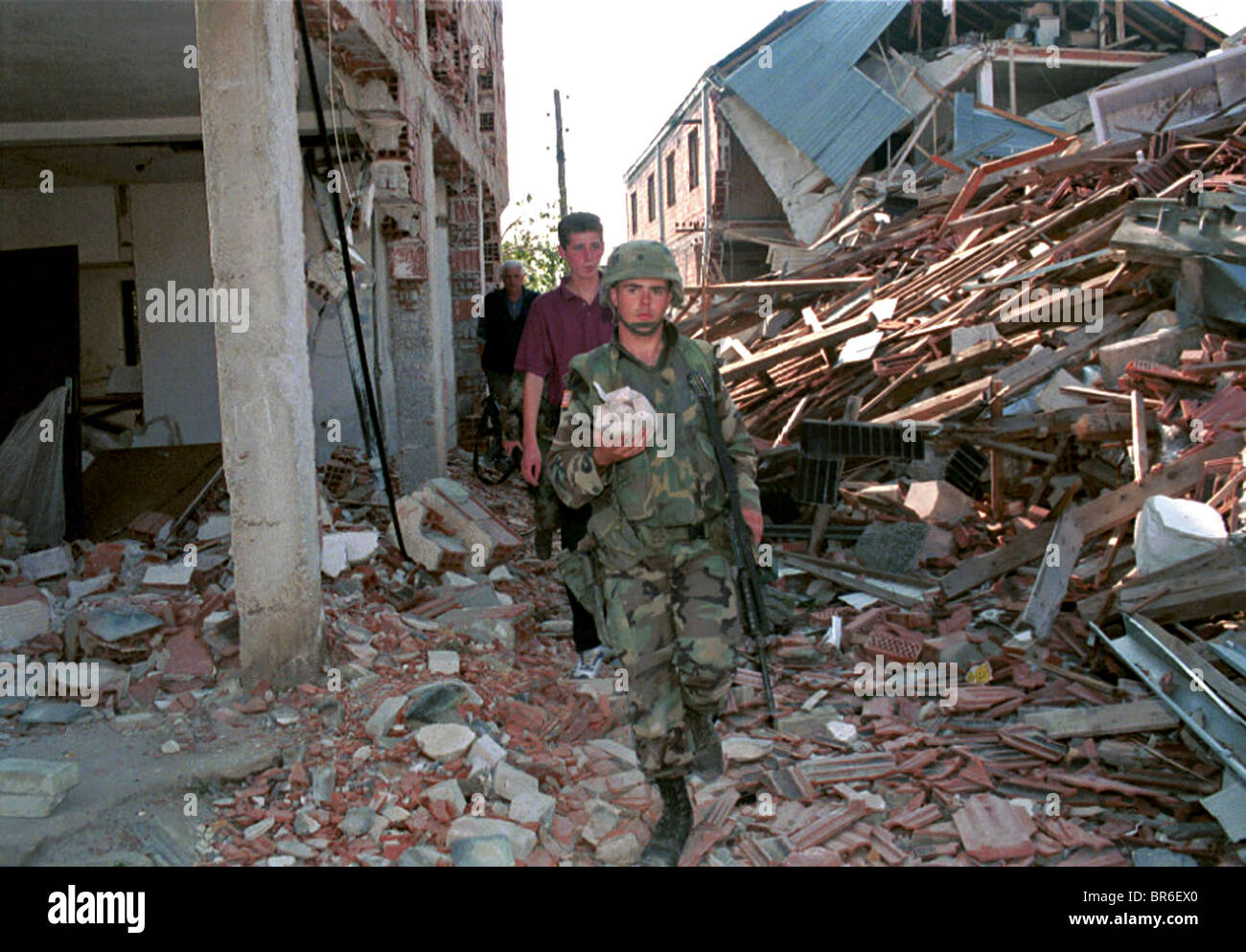 An American soldier removes plastic explosives from a bombed building outside Pristina, Kosovo. Stock Photo