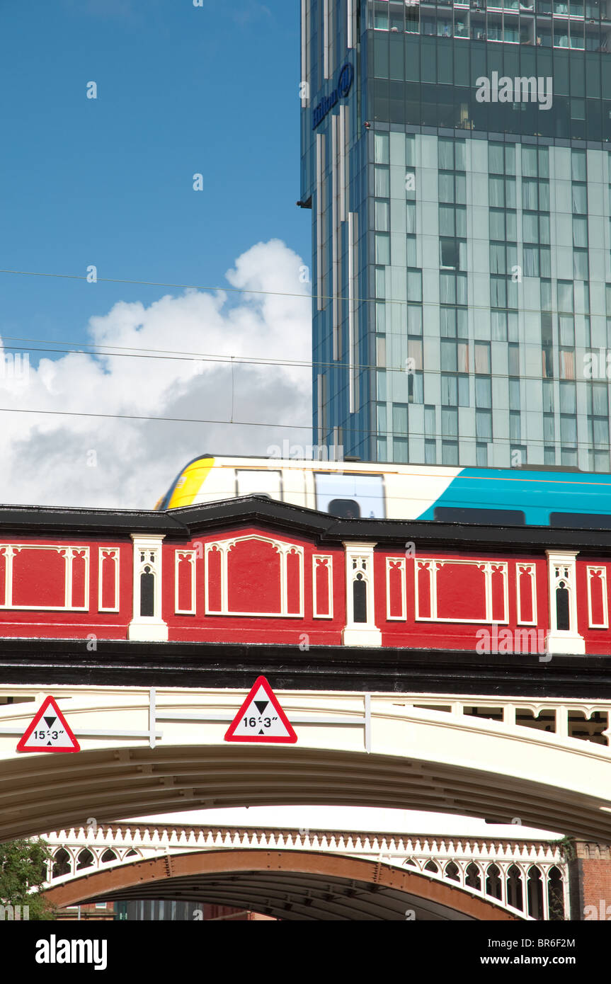 An Arriva train travel across the bridge at the Castlefield end of Deansgate,Manchester,UK/Behind is Beetham Tower,Hilton Hotel Stock Photo